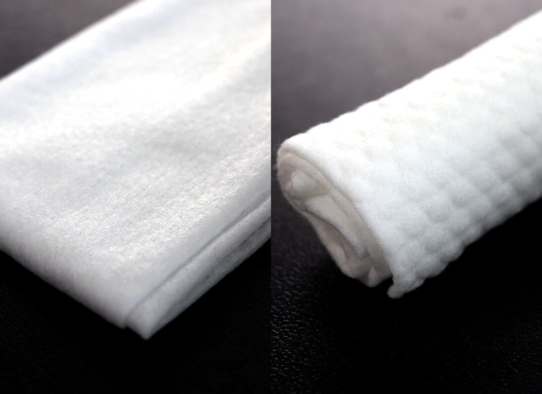 A folded white refresher towel beside a rolled one
